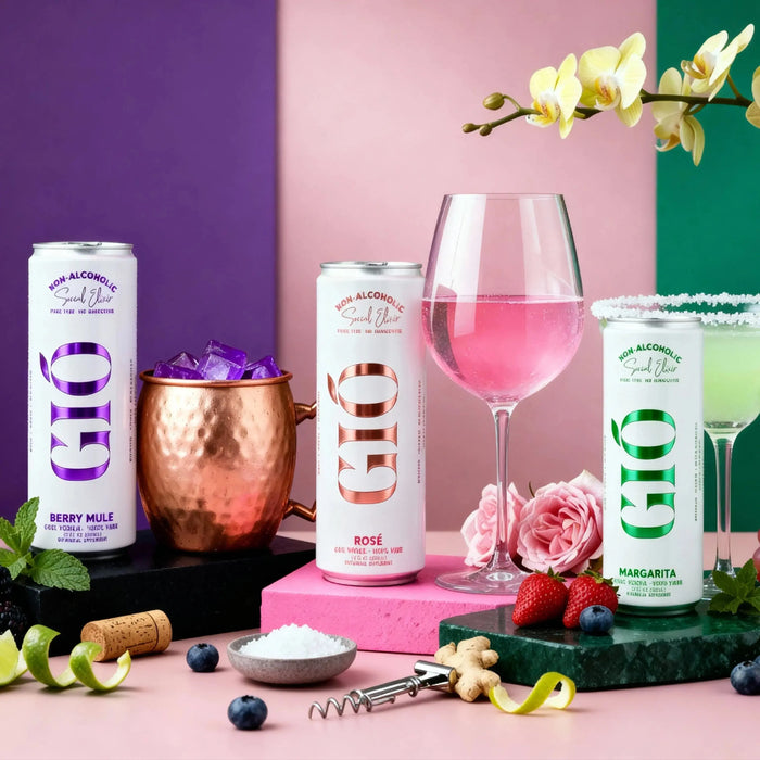 Vibrant flat lay of three canned non-alcoholic cocktails with a pink drink in a wine glass, copper mug with ice, fruits and flowers on colorful pastel background for premium beverage brand marketing.
